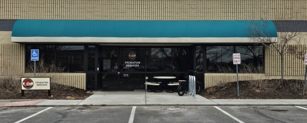 Parking lot and front of Midpoint Office. Green awning on beige building.